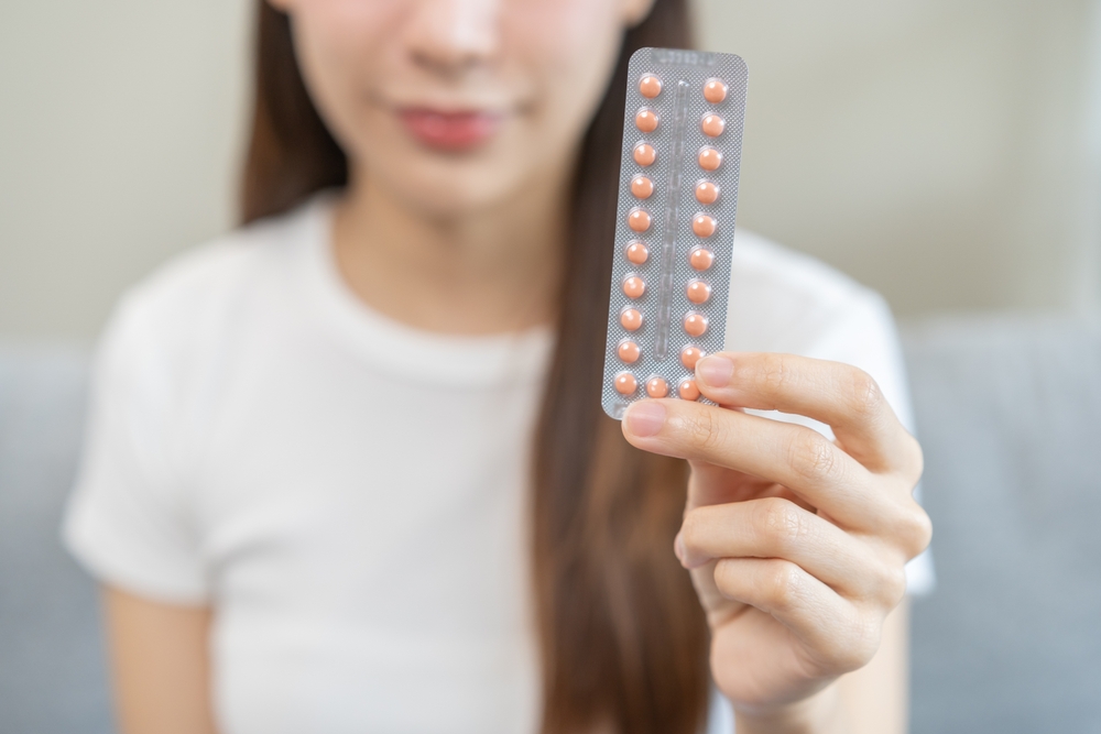 Emergency contraception and pregnancy concept asian young woman hand holding birth control pills, hormonal oral contraceptive medicine at home, take pharmaceutical to prevention virus sex disease.