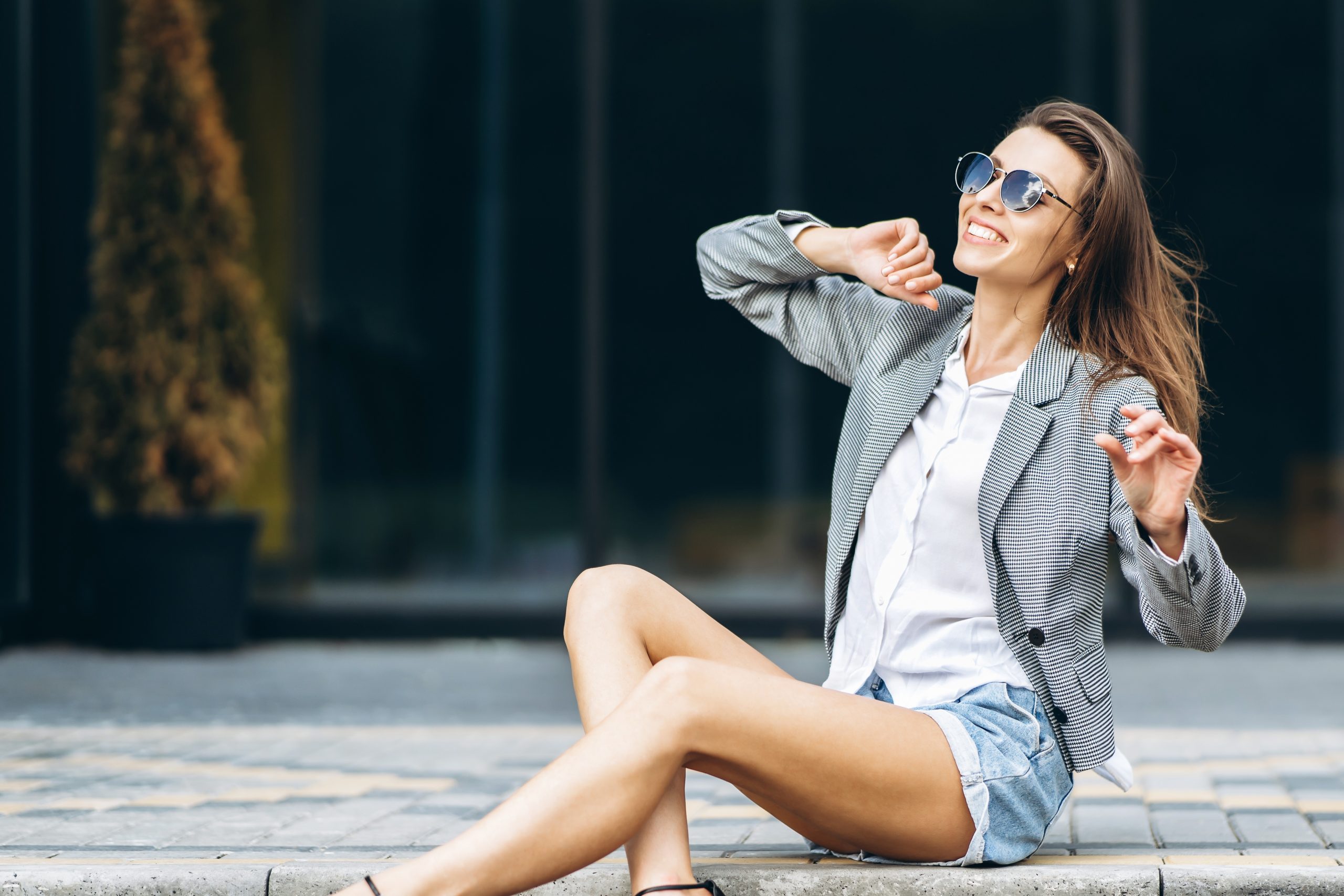Smiling woman wearing sunglasses sitting outdoors in casual attire, expressing confidence, independence, and a positive women’s healthcare experience – obgyn margate