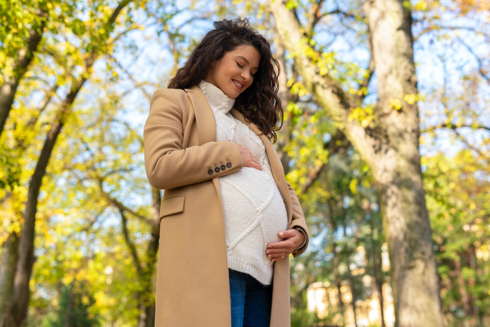 Expectant mother gently holding her baby bump while standing outdoors, representing compassionate prenatal care at a trusted women’s health center – trusted women’s health center 