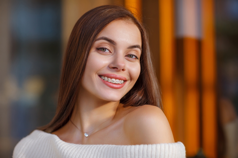 Young woman smiling brightly with braces in a warm, welcoming setting, reflecting approachable, high-quality care at a medical office – pompano beach clinic