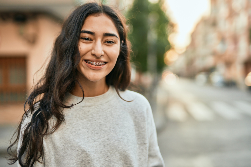 Young woman smiling on a quiet city street in natural light, reflecting confidence, comfort, and patient-centered women’s healthcare – obgyn north miami beach