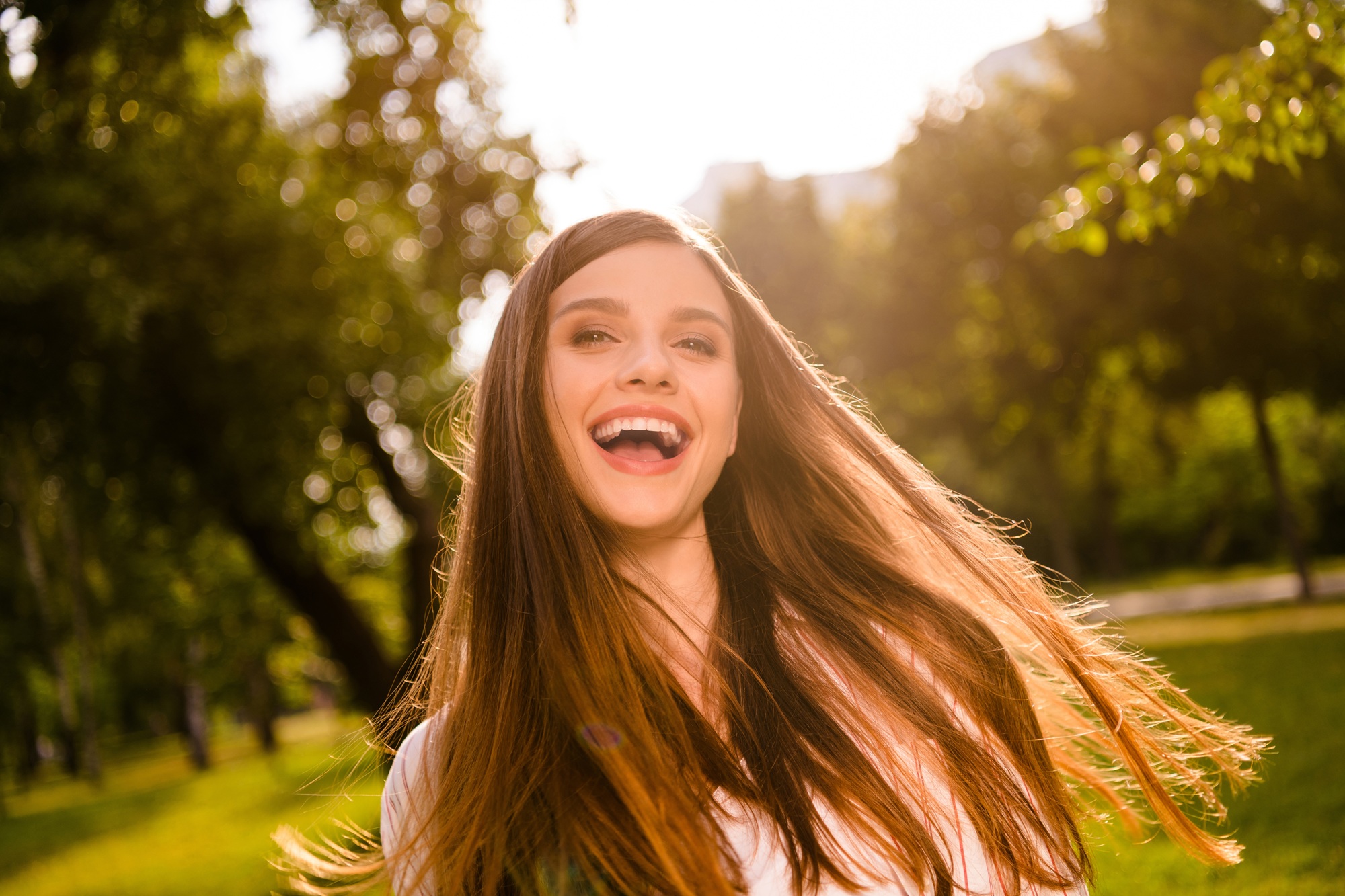 Happy young woman with flowing hair smiling outdoors in natural sunlight, representing vitality, confidence, and compassionate women’s healthcare – obgyn margate