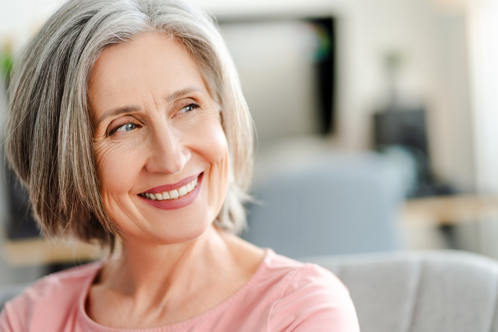 Mature woman smiling while seated comfortably indoors, reflecting trust, comfort, and compassionate women’s healthcare services – obgyn north miami beach